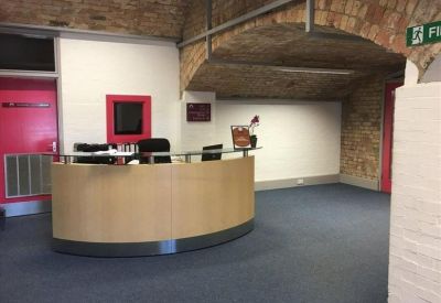 Curved wooden reception desk under an industrial brick archway.