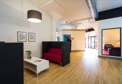 Breakout space with a red sofa, white coffee table, and a private meeting pod.
