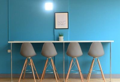 High bar counter with grey stools against a bright blue feature wall.