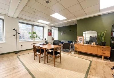 Bright dining area with a mid-century wooden table and a green feature wall.