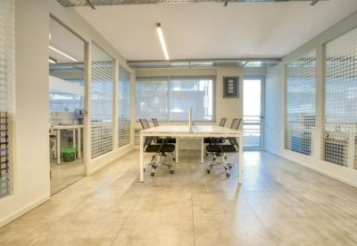 Spacious coworking area with white desks and glass-partitioned offices.
