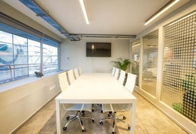 Modern conference room with a long white table and frosted glass walls.
