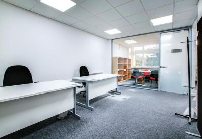 Private internal two-person office suite with white desks and glass partitioning.