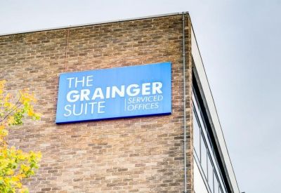 Exterior brick facade featuring a blue building identification sign for the office suite.
