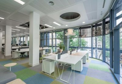 Bright open-plan workspace with a curved glass wall and colorful checkered carpet.