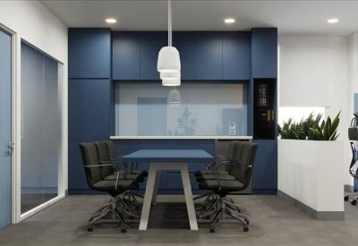 Communal breakout area with a blue table, pendant light, and indoor plants.