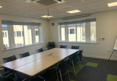 Professional meeting room with a large wooden table and grey carpeting.