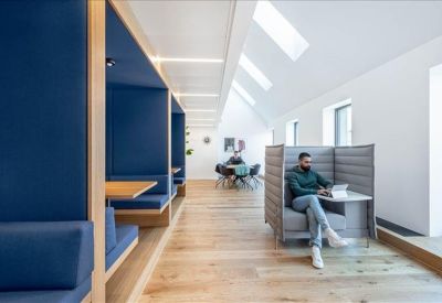 Minimalist corridor with blue acoustic work booths and natural light.