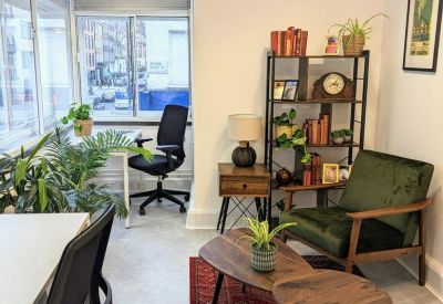 Cozy corner office area with a green velvet armchair and wooden shelving.