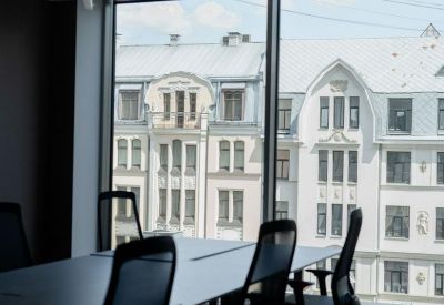 Modern conference room with a long table and black chairs overlooking historic city buildings.