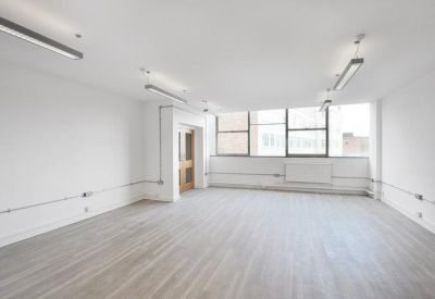 Bright, empty open-plan office with white walls and light wood flooring.