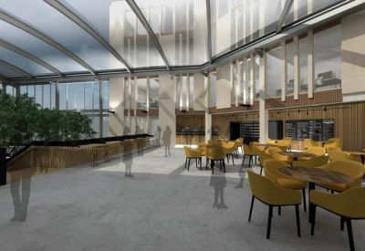 Communal dining area with yellow chairs, wooden tables, and a large skylight roof.