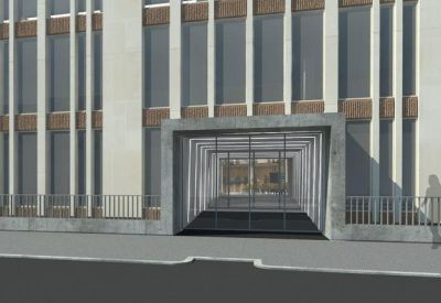 Modern glass-enclosed building entrance viewed from the street sidewalk.