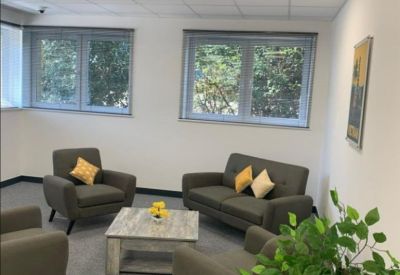 Lounge area with grey armchairs, yellow accent pillows, and large windows.