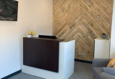 Reception area featuring a dark wood desk and a geometric light wood feature wall.