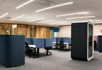 A light-filled breakout room featuring a long white table, modern pendant lights, and refreshments.