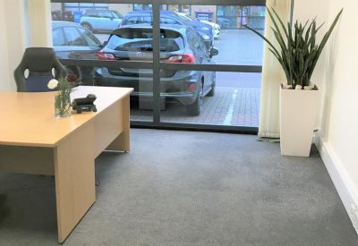 Private office space with a desk and large window overlooking the parking area.