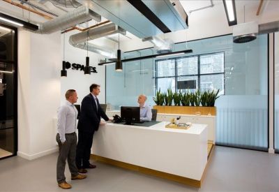 Bright reception area with white desk, plants, and industrial ceiling details.
