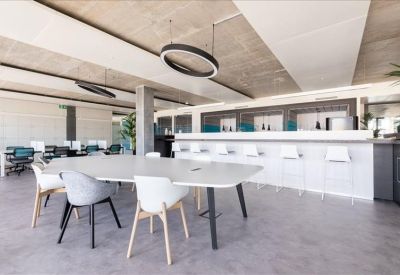 Communal break area with a long white table and bar stool seating.