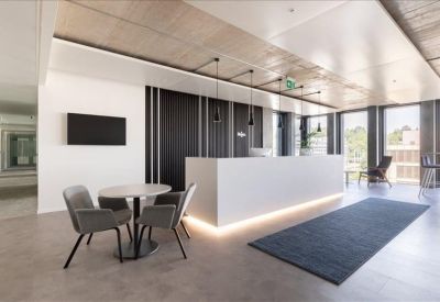 Bright reception area featuring a minimalist white front desk and a small seating area.