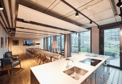 Modern communal kitchen and dining area with a long wooden table and pendant lighting.