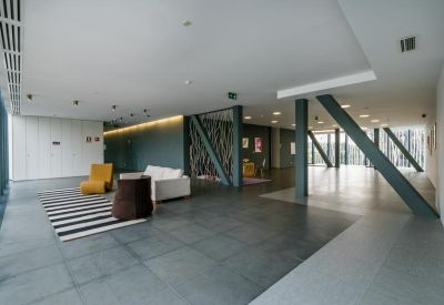 Spacious open lobby with a striped rug and modern structural pillars.