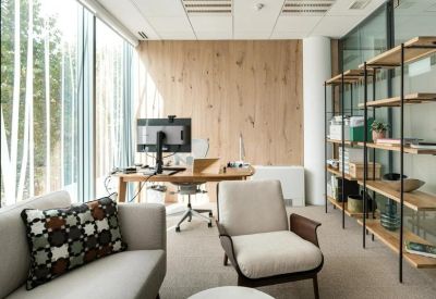 Modern private office with a wooden feature wall and plush grey seating.
