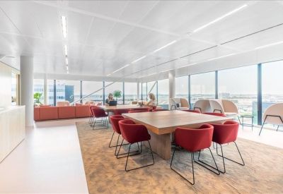 Spacious coworking area with a large wooden table and bright red chairs.