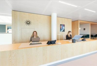 Elegant reception area with a light-wood front desk and a designer wall clock.