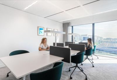 Modern workspace with white desks, privacy partitions, and teal rolling chairs.