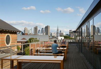 Rooftop terrace with wooden benches and views of the London skyline.