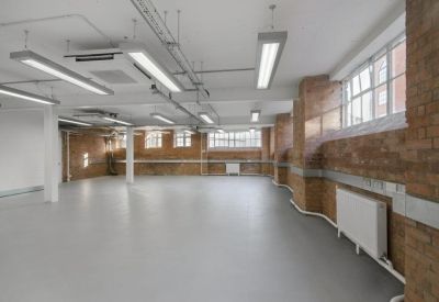 Large open-plan office space with exposed brick walls and grey flooring.