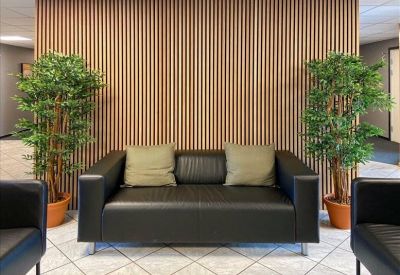 Small waiting area featuring a black leather sofa with green cushions against a wood-slat wall.