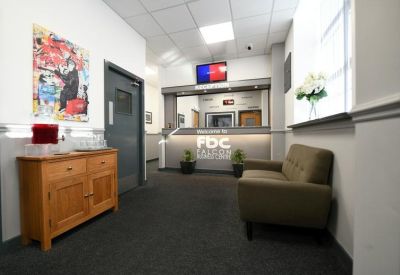 Modern reception lobby with a grey front desk, seating, and colourful wall art.