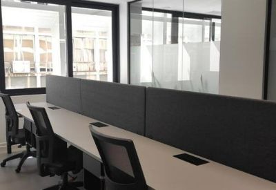 Modern workstations with grey privacy screens and black ergonomic chairs.
