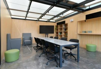 Meeting room with a long white table, black chairs, and a large wall-mounted monitor.