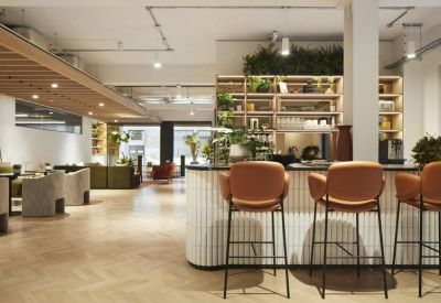 Reception and cafe area featuring a white tiled bar with leather stools and warm herringbone flooring.