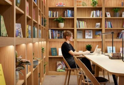 Quiet library workspace with floor-to-ceiling wooden bookshelves and a long desk.