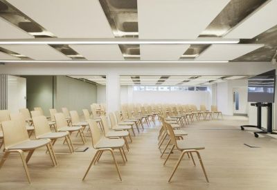 Large presentation room with rows of light wood chairs and acoustic ceiling panels.