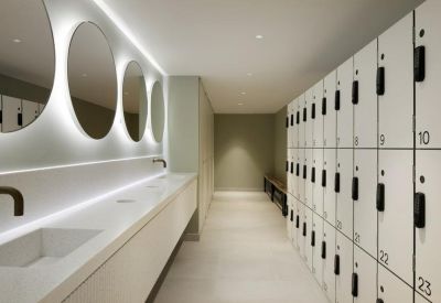 Bright locker room and washroom area with white circular mirrors and numbered lockers.