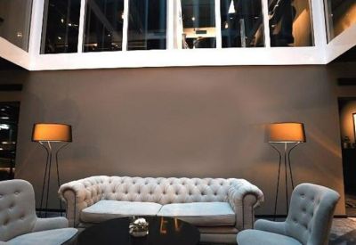 Lounge area with a tufted grey sofa, matching armchairs, and warm designer floor lamps.