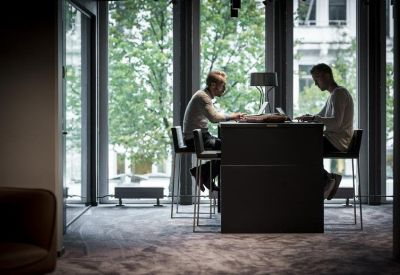 Coworking space featuring two people working at a high table in front of large windows.