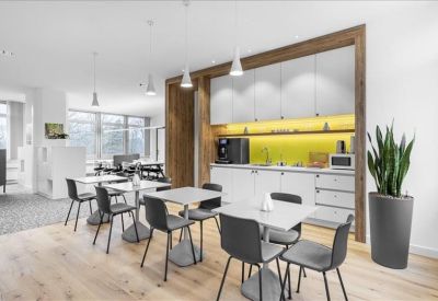 Modern communal kitchen and dining area with white cabinets and a yellow backsplash.
