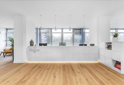 Minimalist reception area with a white marble-effect desk and warm wood flooring.