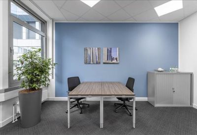 Bright private office with blue feature wall, two desks, and large window.