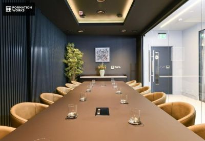 Sophisticated boardroom with a long dark wood table, leather chairs, and accent lighting.