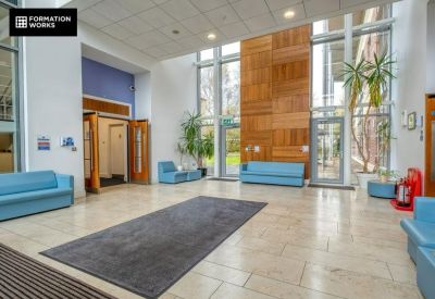 Spacious light-filled reception lobby with high ceilings, blue sofas, and wooden wall panels.
