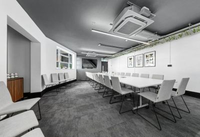 Long boardroom with a white conference table and modern grey ceiling.
