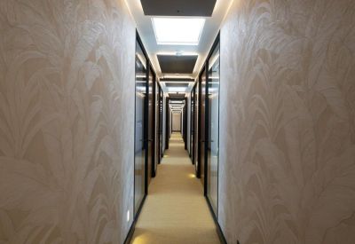 Long bright hallway with glass doors and decorative botanical wallpaper.