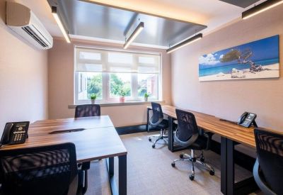 Spacious multi-desk office with wooden tables and beach mural.